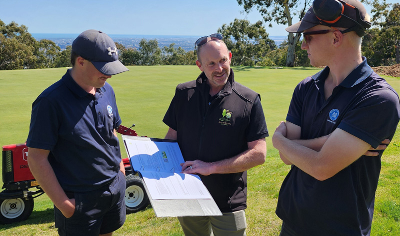 3 landscapers standing discussing job with open folder